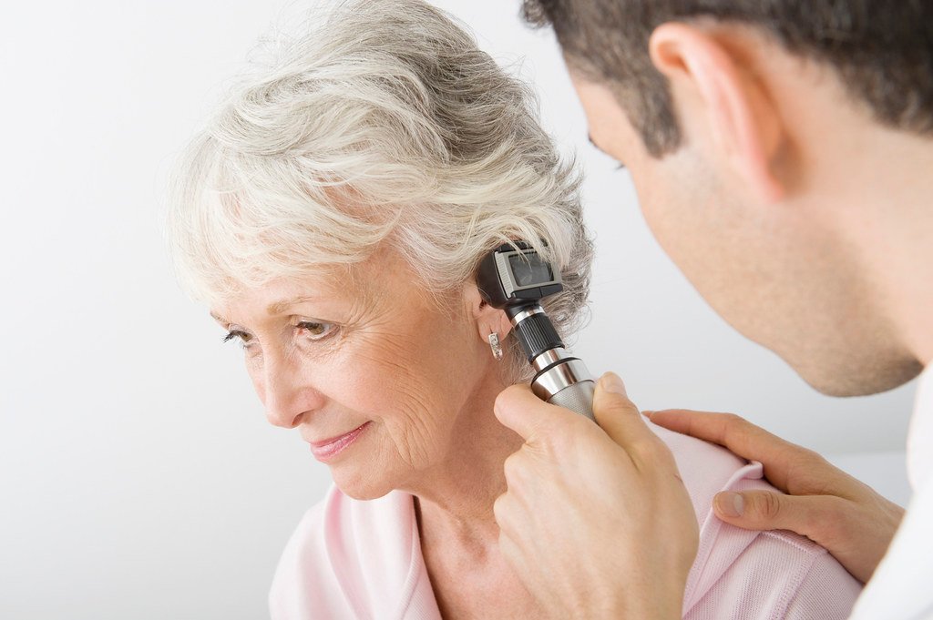 doctor examining patients ear with otoscope