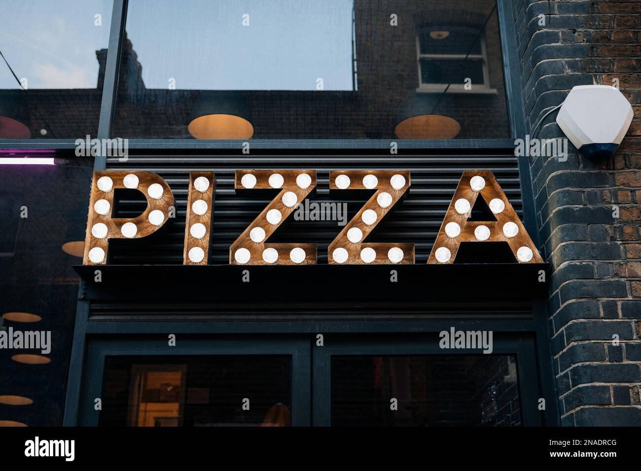 fachada de una pizzeria con letrero iluminado