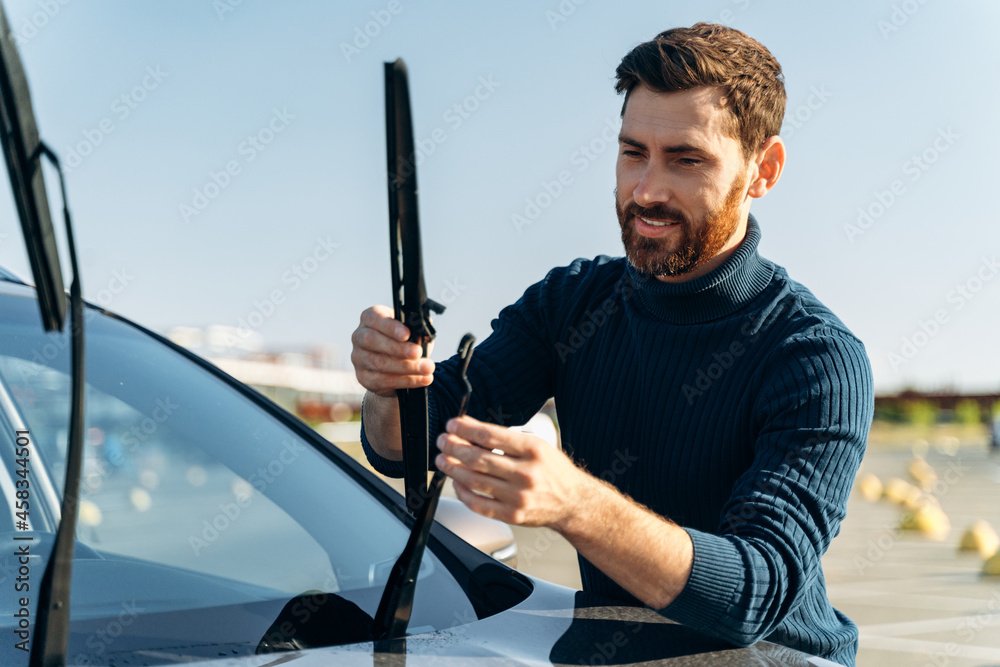 man repairing car windshield on a street