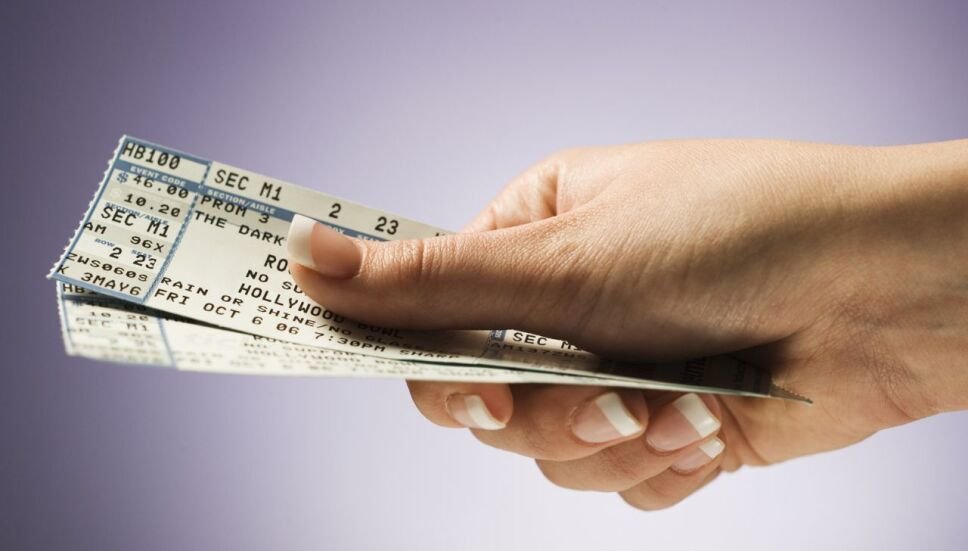 mano sosteniendo varios tickets de eventos