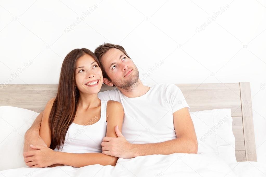 pareja feliz en cama sonriendo juntos