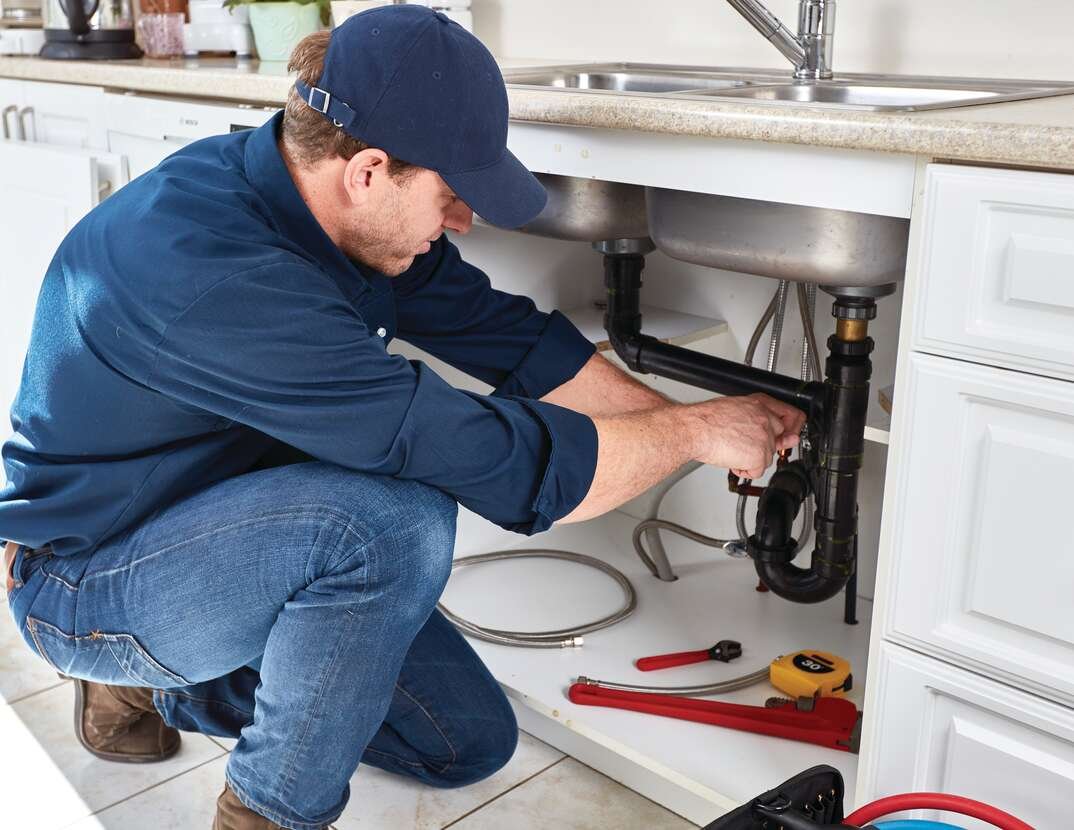 plumber fixing a sink in kitchen