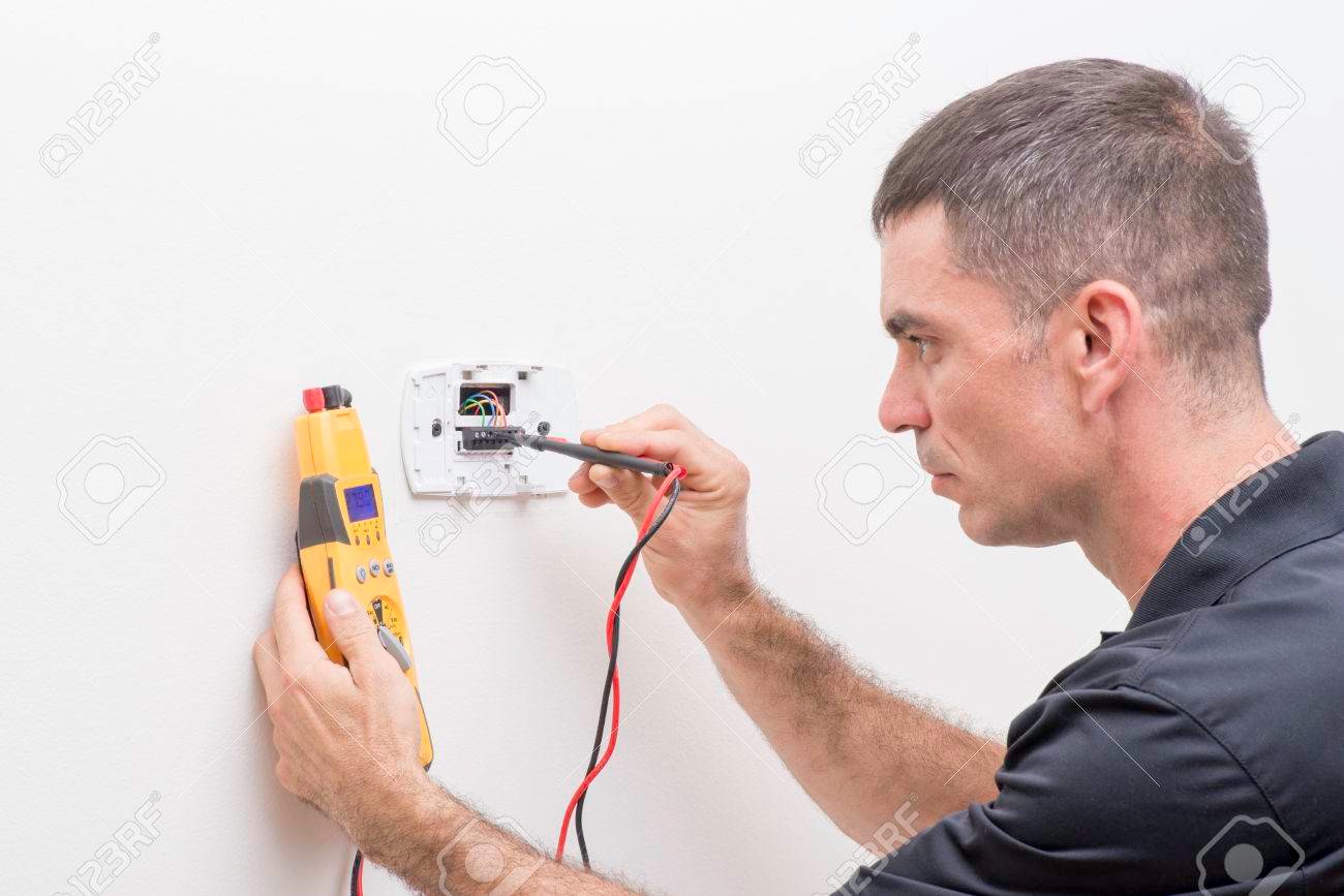 tecnico de hvac revisando un termostato